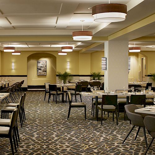 The image shows an upscale, empty restaurant interior with neatly arranged tables, elegant lighting, and modern decor, creating a cozy ambiance.