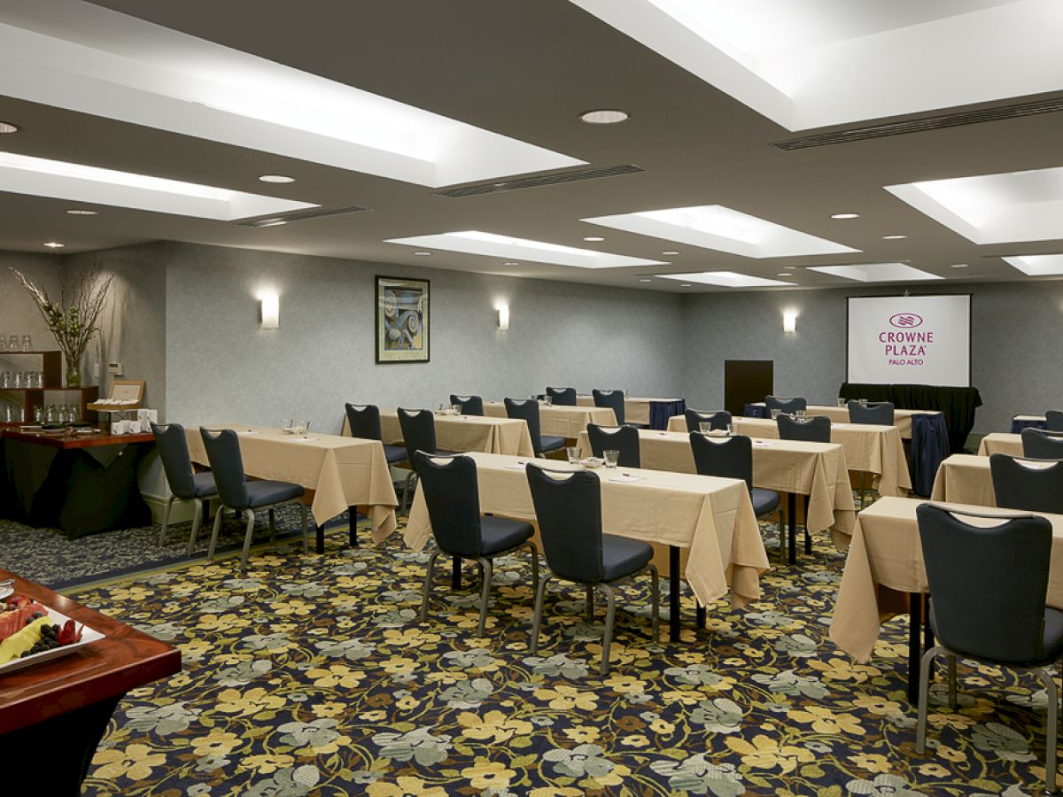 This image shows a conference room with tables set up for a presentation. A screen displays 
