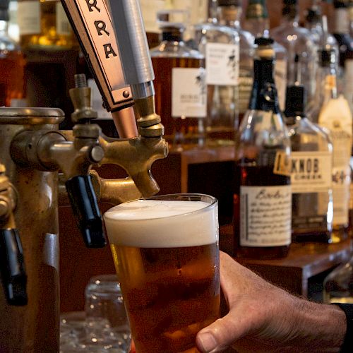 A person is pouring a glass of beer from a tap labeled 